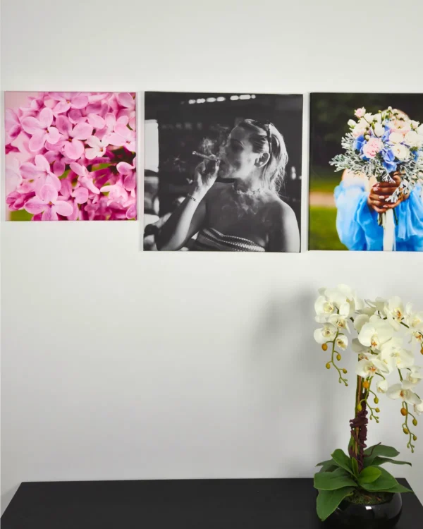 Tryptyk fotoobrazów ze zdjęcia na płótnie na ścianie we wnętrzu z kwiatami i portretem